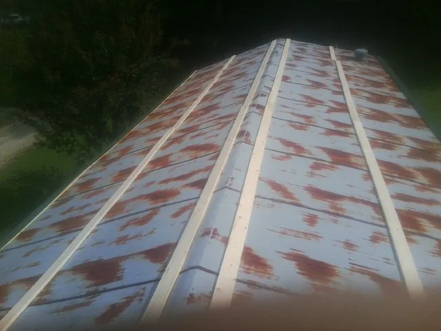 Rusted metal roof panels with new wood purlins before replacement — Storm Damage Roof Repair in Cottage Grove by Roofing Brothers