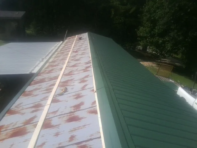 Old rusted panels beside newly installed green metal roofing — Wind Damage Roof Repair by Roofing Brothers in Cottage Grove