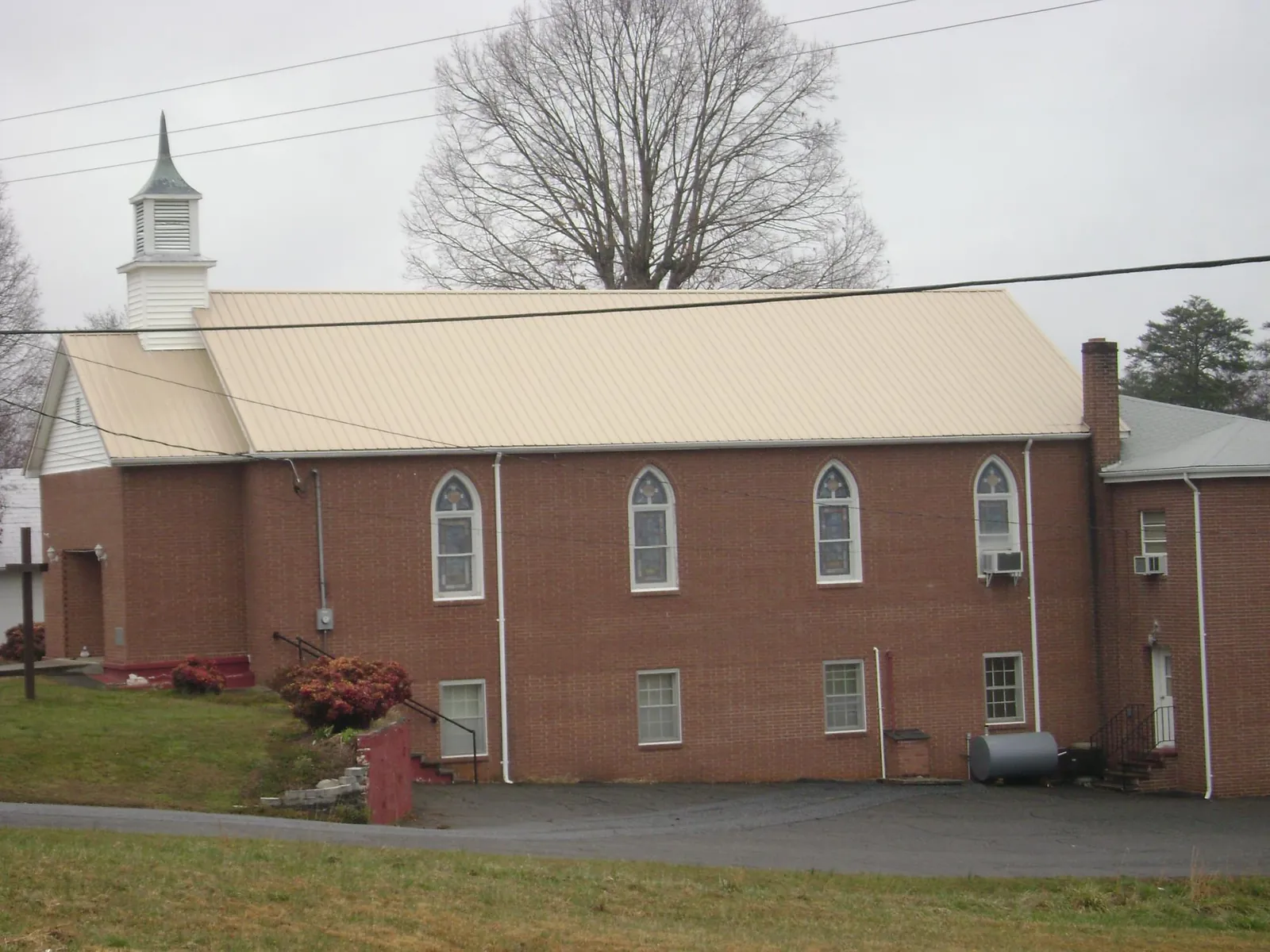 New tan metal roof on a brick church with a white steeple in Cottage Grove